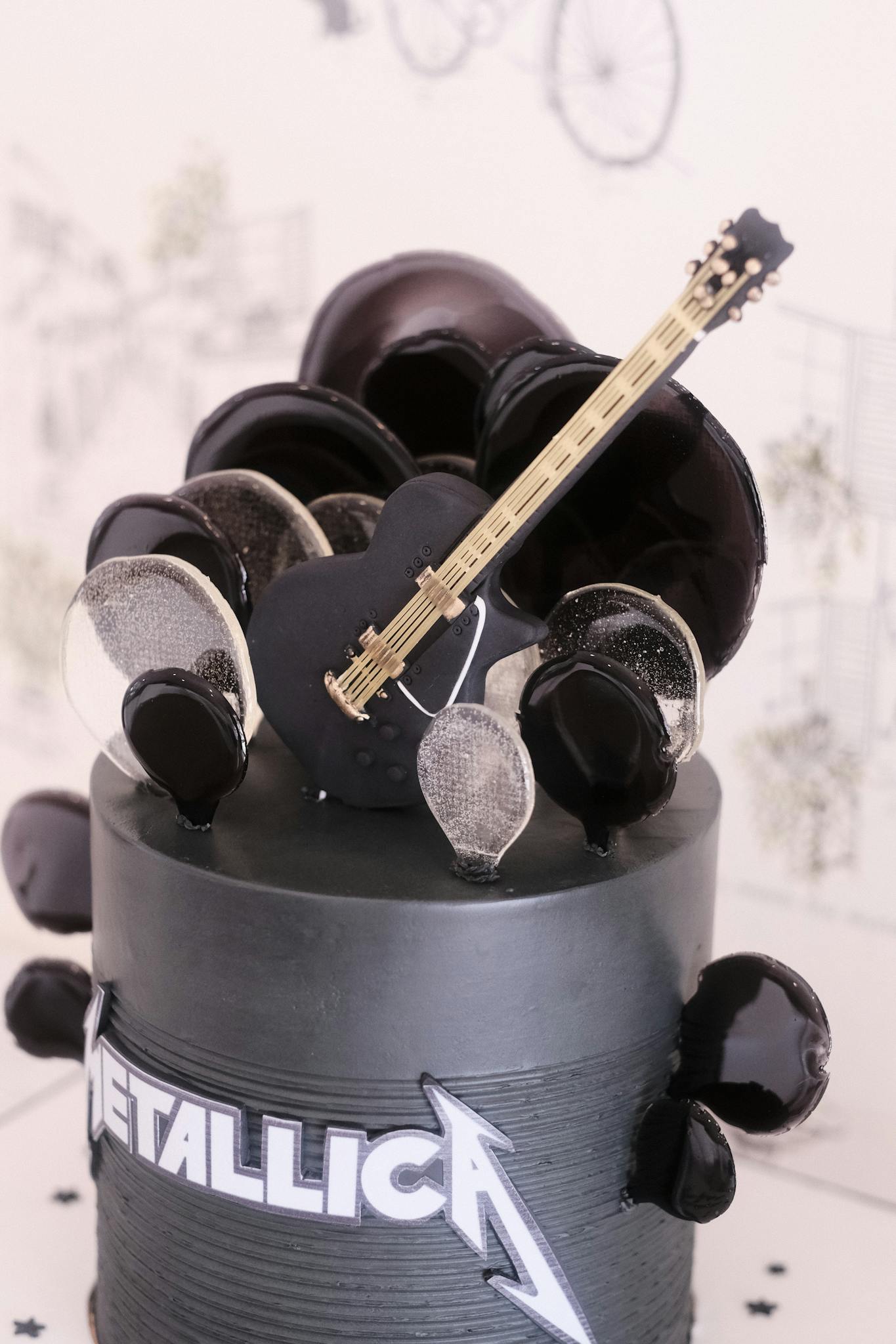 Rock-themed cake featuring a guitar topper and black decor, inspired by Metallica.